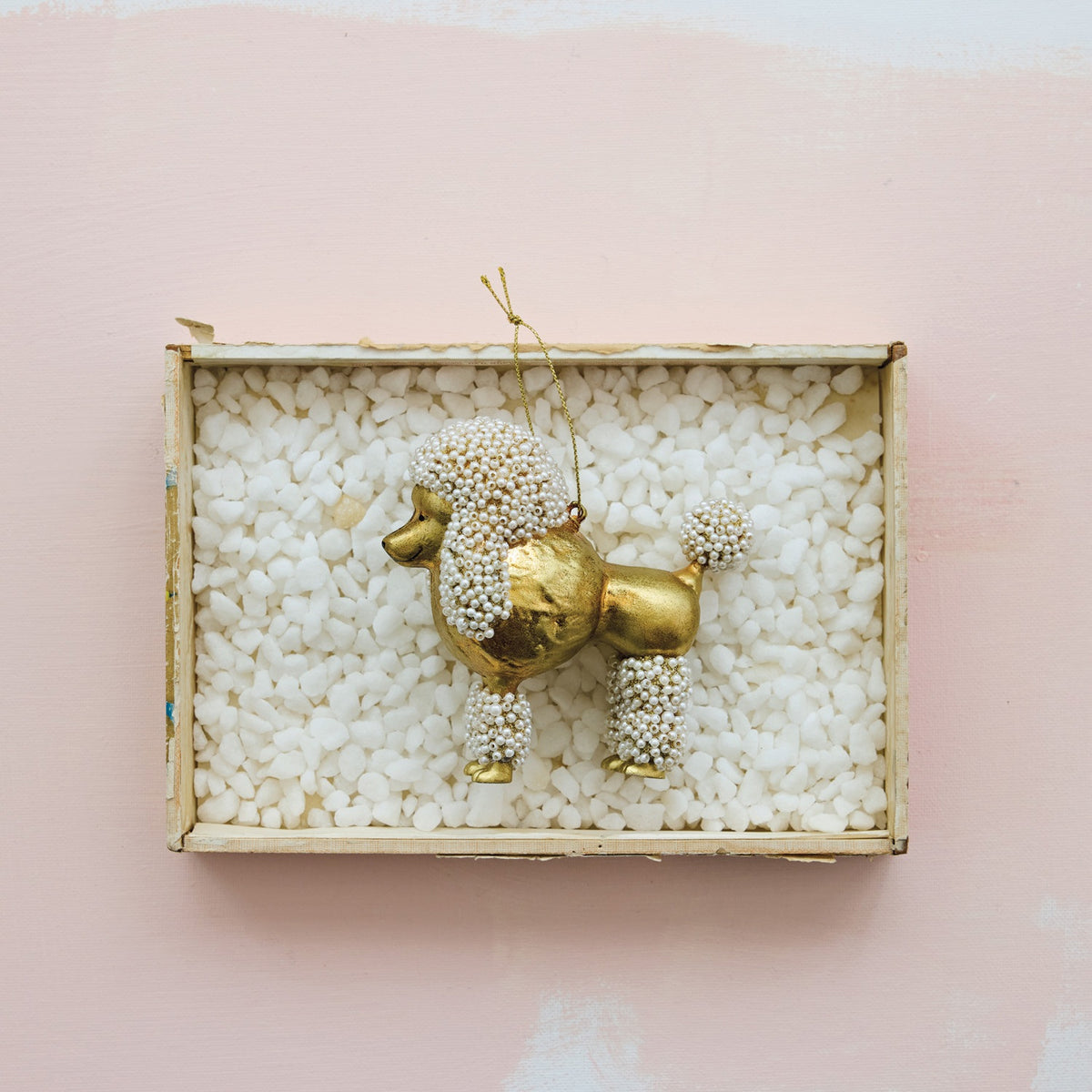 POODLE ORNAMENT WITH FAUX PEARLS, a gold glass poodle decorated with faux pearls on its head, tail, and legs, suspended by a gold string.