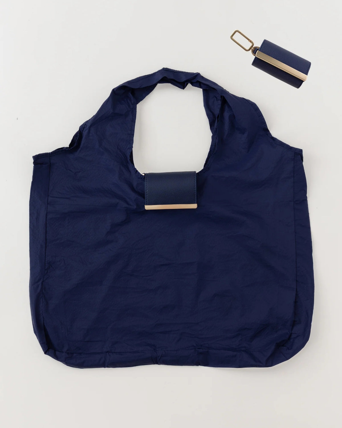 The KEOTE - KEYCHAIN TOTE IN NAVY by KEOTE is shown flat with its matching rectangular case and keychain above it, combining easy storage and style—a perfect purse accessory set against a plain, light background.