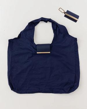 The KEOTE - KEYCHAIN TOTE IN NAVY by KEOTE is shown flat with its matching rectangular case and keychain above it, combining easy storage and style—a perfect purse accessory set against a plain, light background.