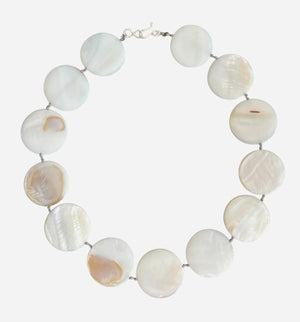 A mannequin is styled with a light gray shawl and showcases the ANN LIGHTFOOT Mother of Pearl Disc Ras du Cou Necklace, featuring large, round white beads and a sterling silver clasp, set against a neutral brown background.