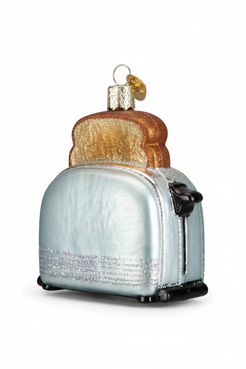 OLD WORLD CHRISTMAS RETRO TOASTER ORNAMENT shaped like a silver pop-up toaster with a golden slice of toast popping out the top.
