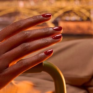 A close-up of MANUCURIST - GREEN™ NAIL POLISH IN BOHEMIAN by MANUCURIST INC being smoothly applied with a brush, revealing its glossy, reflective red finish and visible bristle strokes.