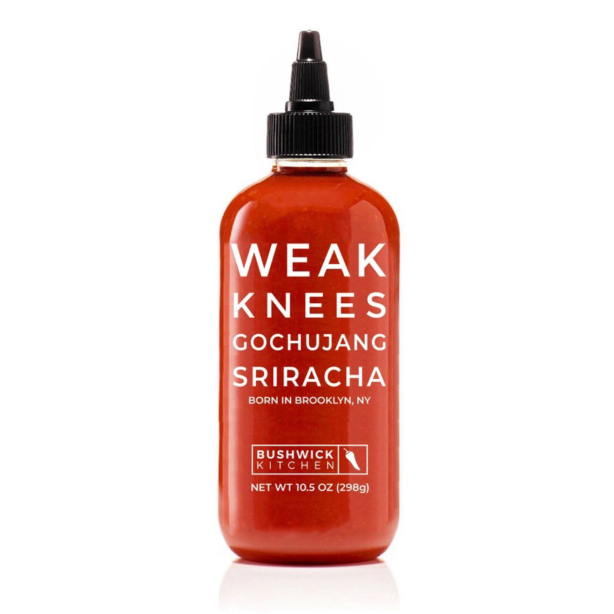 A 10.5 oz (298g) bottle of BUSHWICK KITCHEN - 'WEAK KNEES' GOCHUJANG SRIRACHA hot sauce features a striking red design with a black cap and white text, proudly made in Brooklyn, NY, USA. This unique blend includes fermented chile paste for an exceptional kick.