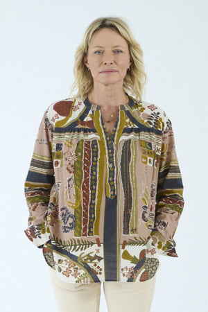 A person with blonde, shoulder-length hair is shown from the back against a plain light background, wearing the STORIATIPIC - MARGOT BLOUSE IN DELYS by STORIATIPIC—a colorful, patterned long-sleeve blouse crafted from 100% cotton for comfort and breathability. This top pairs effortlessly with light pants and is ideal for gentle machine wash and easy cotton care.