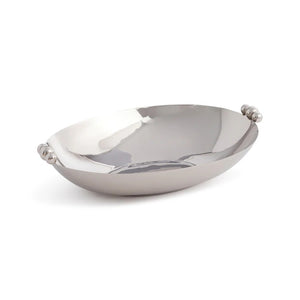 The ZODAX POLISHED NICKEL SERVING BOWL, featuring small rounded handles on each end, is displayed on a glittery surface with sparkling cubic decorations in the background.