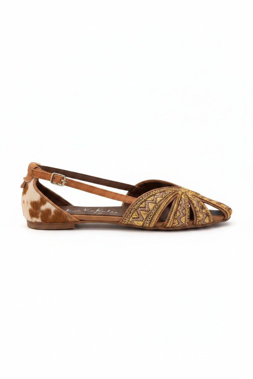 The MEHER KAKALIA - QUEEN DORIS SLING BACK IN KHAKI GOLD is a handcrafted women’s flat sandal in brown and yellow tones, featuring geometric embroidered patterns and cutout details. Viewed from the side, this artisanal footwear by MEHER KAKALIA showcases elegant embroidery and refined styling with a distinctive flair.