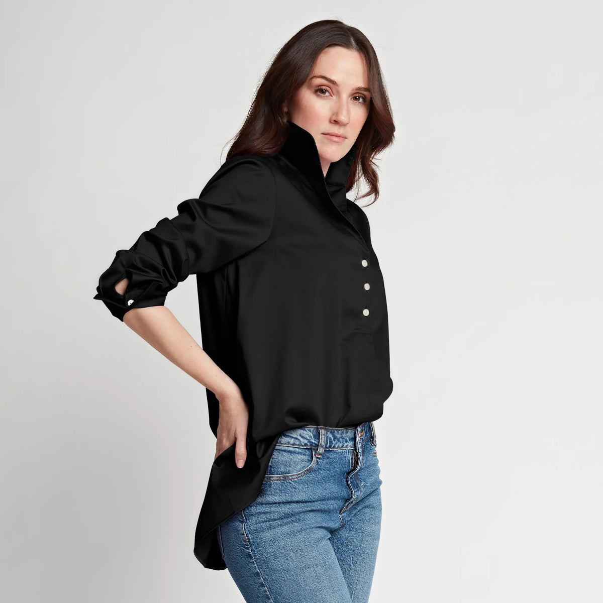 A person with short brown hair stands against a plain white background, wearing the HINSON WU - BETTY LONG SLEEVE TUNIC with the sleeves rolled up to the elbows and black pants. One hand is tucked into their pocket, and they look confidently at the camera.