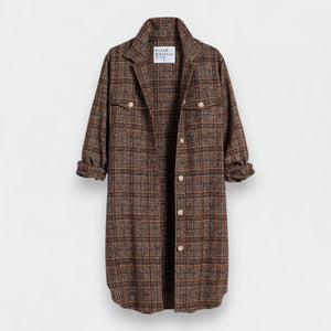 The Gavin Italian Boucle Shirt Jacket from Frank & Eileen is a long, plaid coat in shades of brown with an oversized fit. Made from luxurious pre-washed wool, the coat features a collared neckline, button closure, and two large front pockets. Sleeves are rolled to mid-length and the fabric showcases a textural, woven appearance. The tag inside reads "Frank & Ellen.