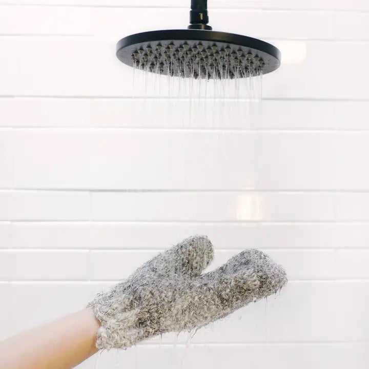 A single, thick, gray BAUDELAIRE - SISAL &amp; HORSEHAIR BATH GLOVE lies flat against a plain white background. The bath glove, resembling a hand-knit mitten, is crafted with a textured pattern that provides a cozy and warm appearance.