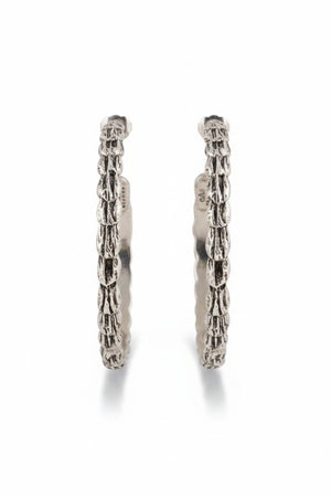 Introducing the GAS BIJOUX - LIANE SILVER HOOP EARRINGS: a stunning pair of 4.5 cm diameter, silver-plated earrings showcasing a twisted rope design set against a light background. These elegant hoops reflect subtle sophistication beneath them.
