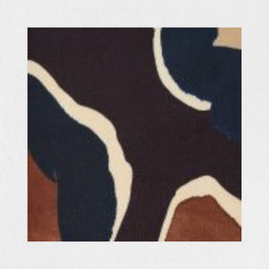 A person with long hair is sporting the ALYKI LABORATORIO PRINTED SATIN JACKET, featuring a green, purple, and brown floral pattern, over a white turtleneck sweater. With one hand in the pocket of their black pants, they perfectly blend an elegant color outfit against a plain white background.