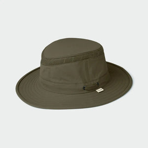 A man with a reddish beard and hair wears a TILLEY AIRFLO Medium Brim LTM5 hat in olive, offering UPF 50+ sun protection, and a beige button-up shirt, looking slightly to the side against a plain light background.