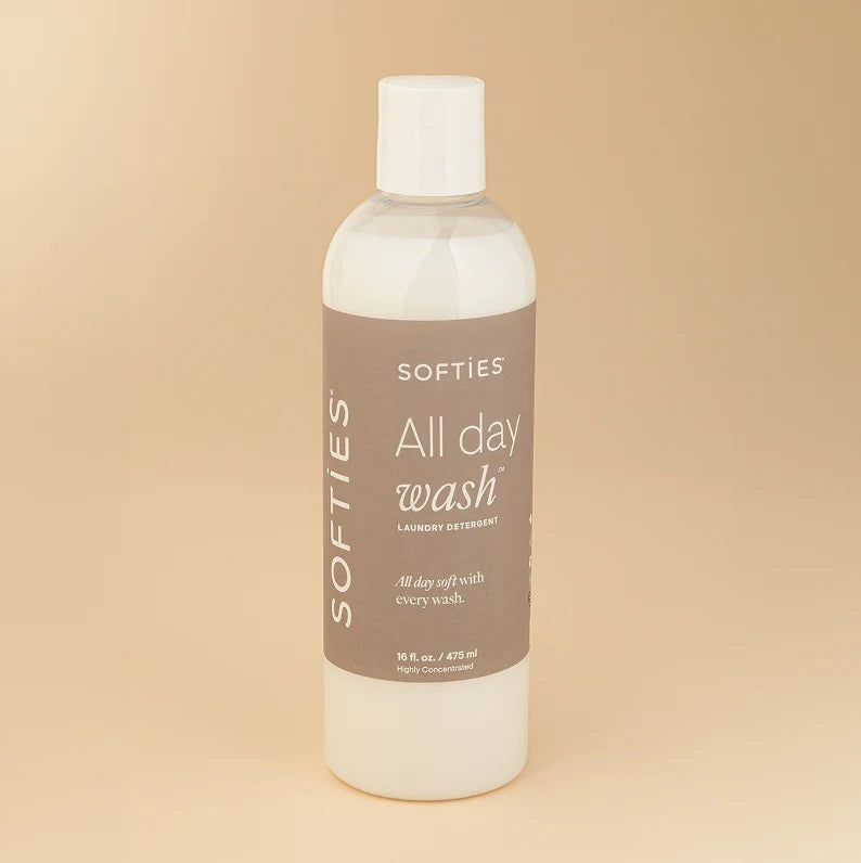 A bottle of SOFTIES - ALL DAY WASH™ LAUNDRY DETERGENT on a white textured surface.