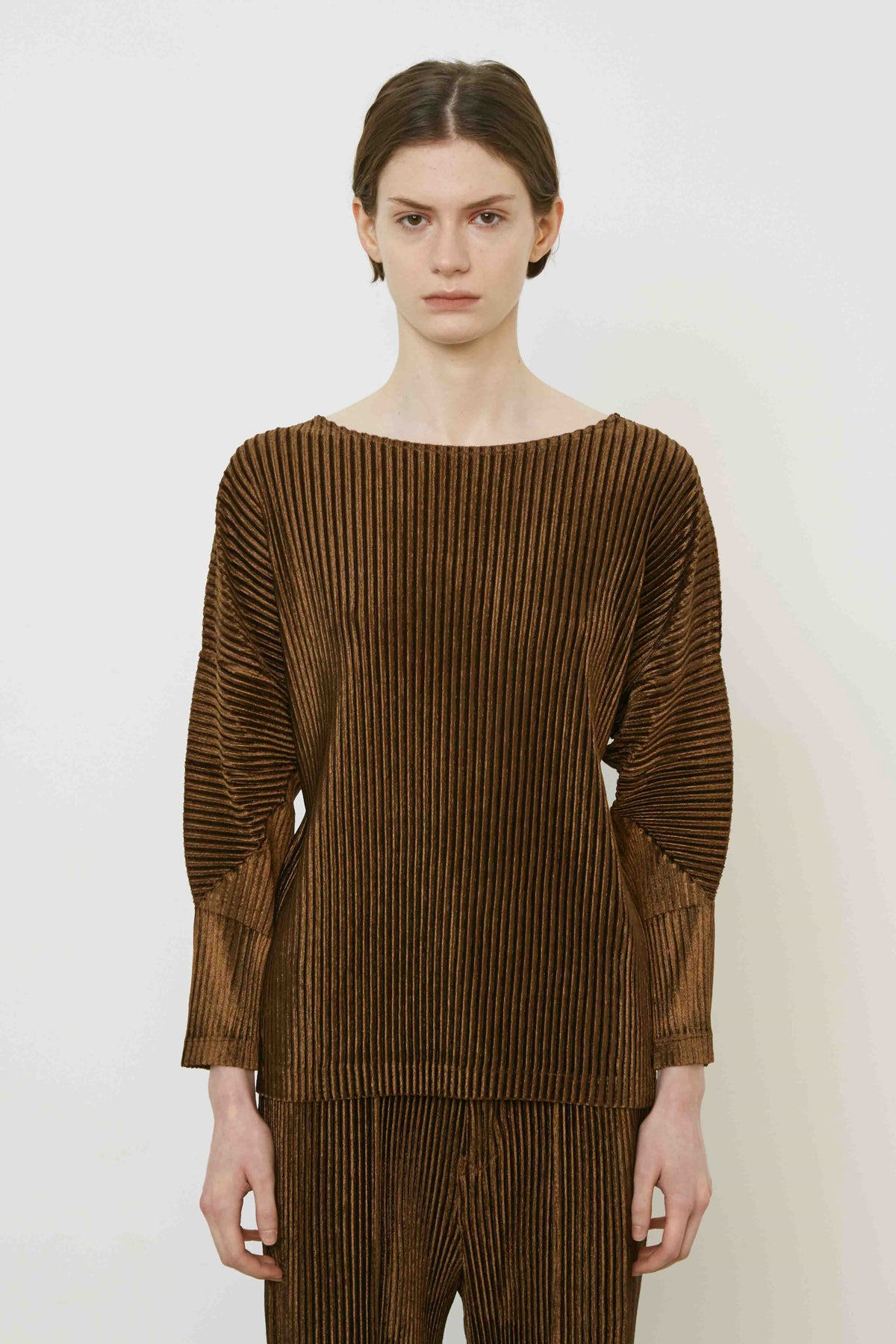 A person with short brown hair stands sideways in a MEIMEIJ - PLEAT TOP by MEIMEIJ against a plain white background, highlighting modern Italian fashion.