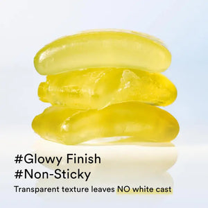 Two black ASIAN BEAUTY WHOLESALE QUICK SUNSTICK PROTECTION BAR 22G are shown: one open, revealing the pale yellow stick, the other closed. A swatch of the portable sunscreen is smeared above them on a white background.