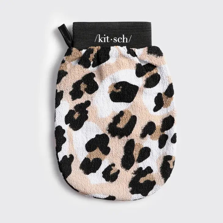 The KITSCH Eco-Friendly Exfoliating Glove boasts a leopard print with black spots on a beige and white background, designed perfectly for bath or shower scrubbing. It features a convenient black tag with white text at the top.