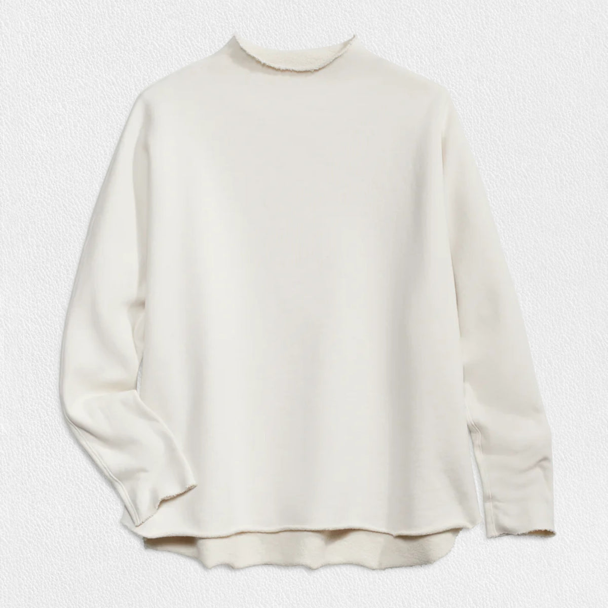 A woman with long brown hair stands smiling near a black grand piano in a modern, well-lit room. She wears the FRANK AND EILEEN - EFFIE LONG SLEEVE FUNNEL NECK CAPELET from FRANK &amp; EILEEN paired with blue jeans. A large window and a lamp are in the background, enhancing the cozy winter warmth of her stylish ensemble.