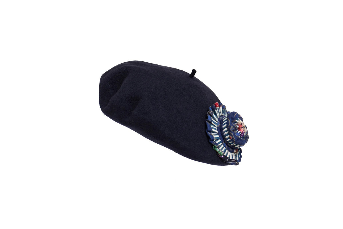 Introducing the LORNA MURRAY - THE AVENUE BERET by LORNA MURRAY: a stylish navy blue beret adorned with an intricate embroidered floral and leaf design on the side. The vibrant colors of the embroidery add a touch of elegance and detail to this classic headwear, crafted from premium Australian wool.