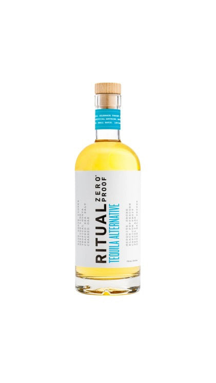 A clear glass bottle of RITUAL ZERO PROOF-TEQUILA ALTERNATIVE by RITUAL ZERO PROOF, a non-alcoholic tequila with a cork top and white label featuring bold black and blue text on a plain background.