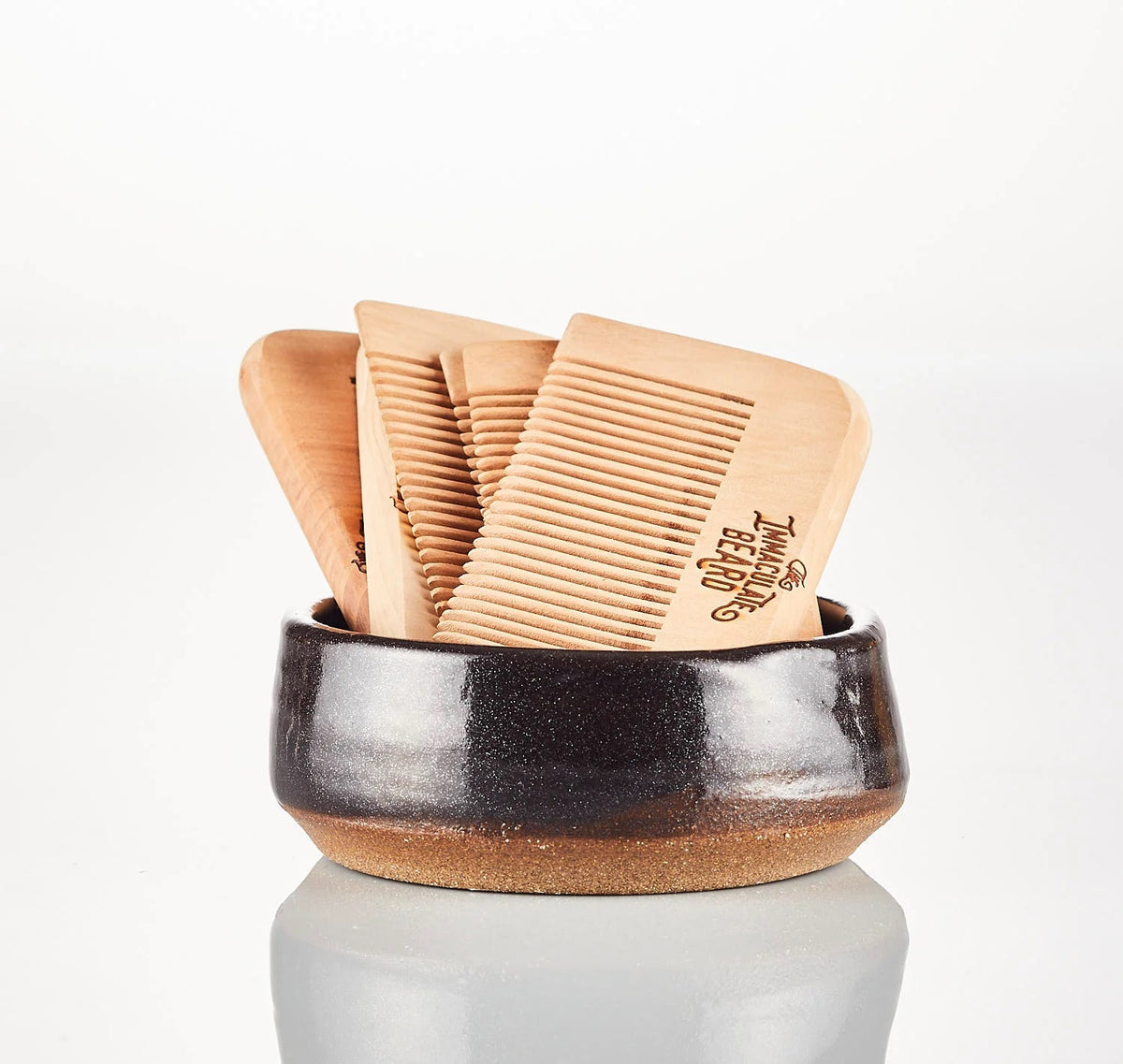 THE IMMACULATE BEARD - WOODEN BEARD COMB by THE IMMACULATE BEARD features laser engraving and stands upright against a light wood surface—ideal for grooming your beard.