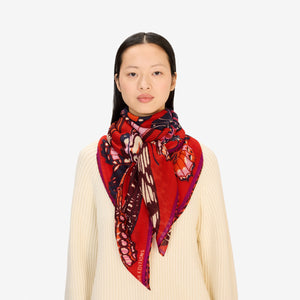 The INOUI EDITIONS PAPILLONS Square Wool Scarf in red features colorful butterflies in pink, orange, purple, and brown across a vibrant 130x130cm design—an eye-catching and versatile accessory for any occasion.