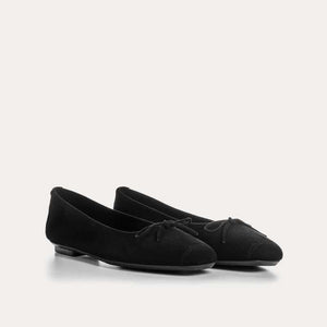 Wearing rolled-up blue jeans with REQINS - HARMONY SUEDE BALLERINA FLATS IN NOIR, featuring chic bow details—a timeless addition to any classic wardrobe.