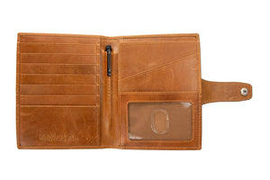 The GARZINI RFID-blocking leather passport holder in cognac features an AirTag compartment and opens to reveal card slots, a pen, and a burgundy passport—combining security with elegant organization.