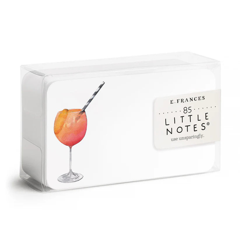 A clear box contains "E. FRANCES PAPER - APEROL SPRITZ LITTLE NOTES" featuring tiny notecards. The front card displays a watercolor of a cocktail with a striped straw and the phrase "use unsparingly.