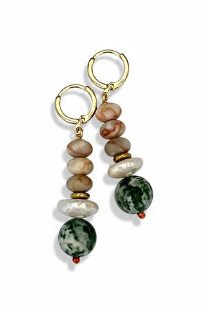 The SELENA EARRINGS by SANDRINE FRANCE STUDIO are gold hoops with stacked beige and brown marbled beads, a white pearl-like accent, gold spacer, and a large green-and-white Tree Agate bead, displayed on a plain background.