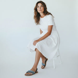 The MEHER KAKALIA - HAMAM SLIDE IN SONIC SAPHIRE by MEHER KAKALIA features a flat wooden sole, teal footbed, blue frayed-edge fabric straps, and yellow and navy textured raffia detail across the top.
