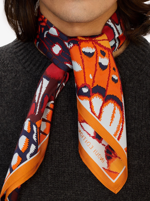 Fearrington Village Inoui Editions Papillons square silk scarf in orange with butterfly wing pattern worn on neck