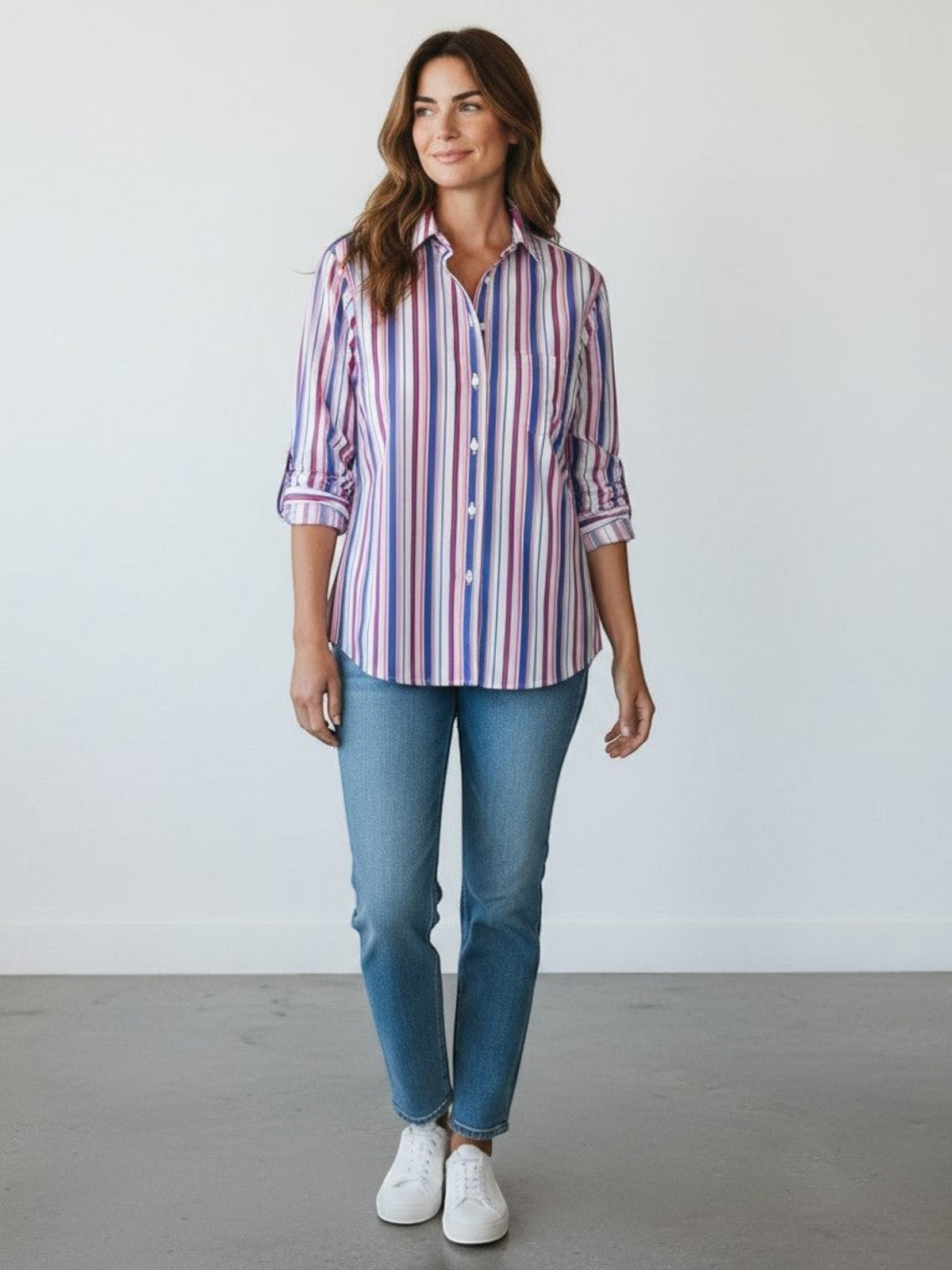 Fearrington Village model wearing a multicolor striped Italian cotton button-up shirt with jeans and white sneakers.