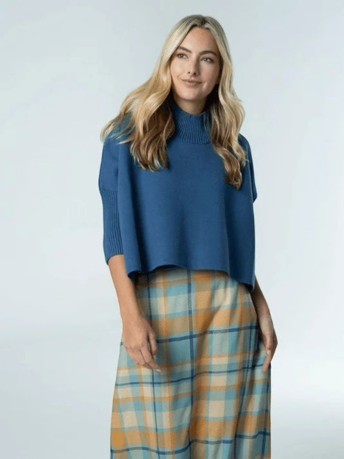 Fearrington Village Sophia oversized dusty navy knit sweater with mock neck and ribbed sleeves worn over a plaid skirt