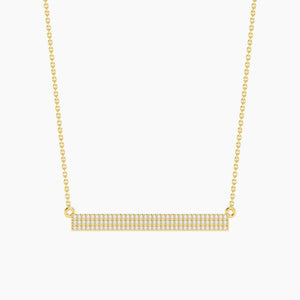 The ELLA STEIN - TELL ME STRAIGHT PENDANT NECKLACE by ELLA STEIN features a gold chain and a horizontal rectangular gold-plated pendant adorned with rows of small, sparkling stones. Displayed against a plain white background, this elegant stainless steel jewelry piece perfectly combines durability with timeless style.
