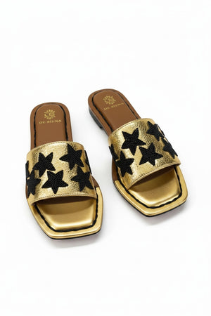 The DE SIENA DA SIENA - BEADED STARS SLIDES are brown and gold metallic open-toe leather slides with a wide strap featuring black beaded star designs and a gold insole outlined in brown with "DE SIENA" branding near the heel.