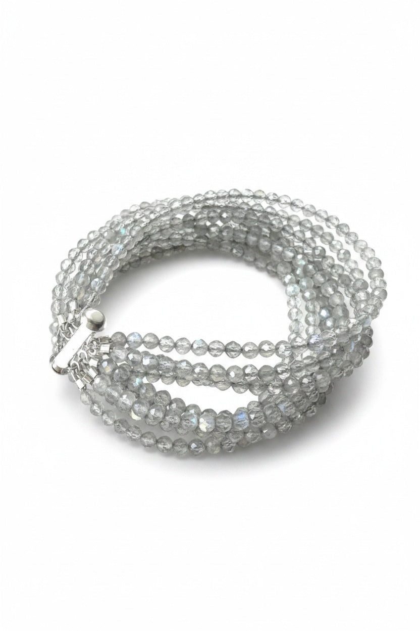 The ANN LIGHTFOOT - NINE STRAND FACETED LABRADORITE CUFF features translucent, faceted grey beads that reflect light for a subtle iridescent effect, coiled neatly and secured with a silver clasp.