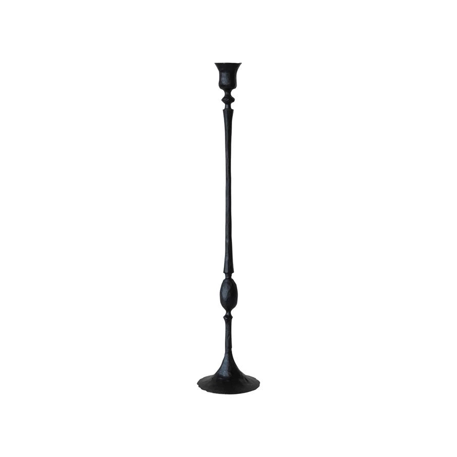 A tall, slender HAND FORGED CAST IRON TAPER HOLDER by CREATIVE COOP, featuring a decorative ball in the middle and a wide base. This black candlestick showcases simple, elegant design elements with rustic charm. The holder is shown without a candle against a plain white background.