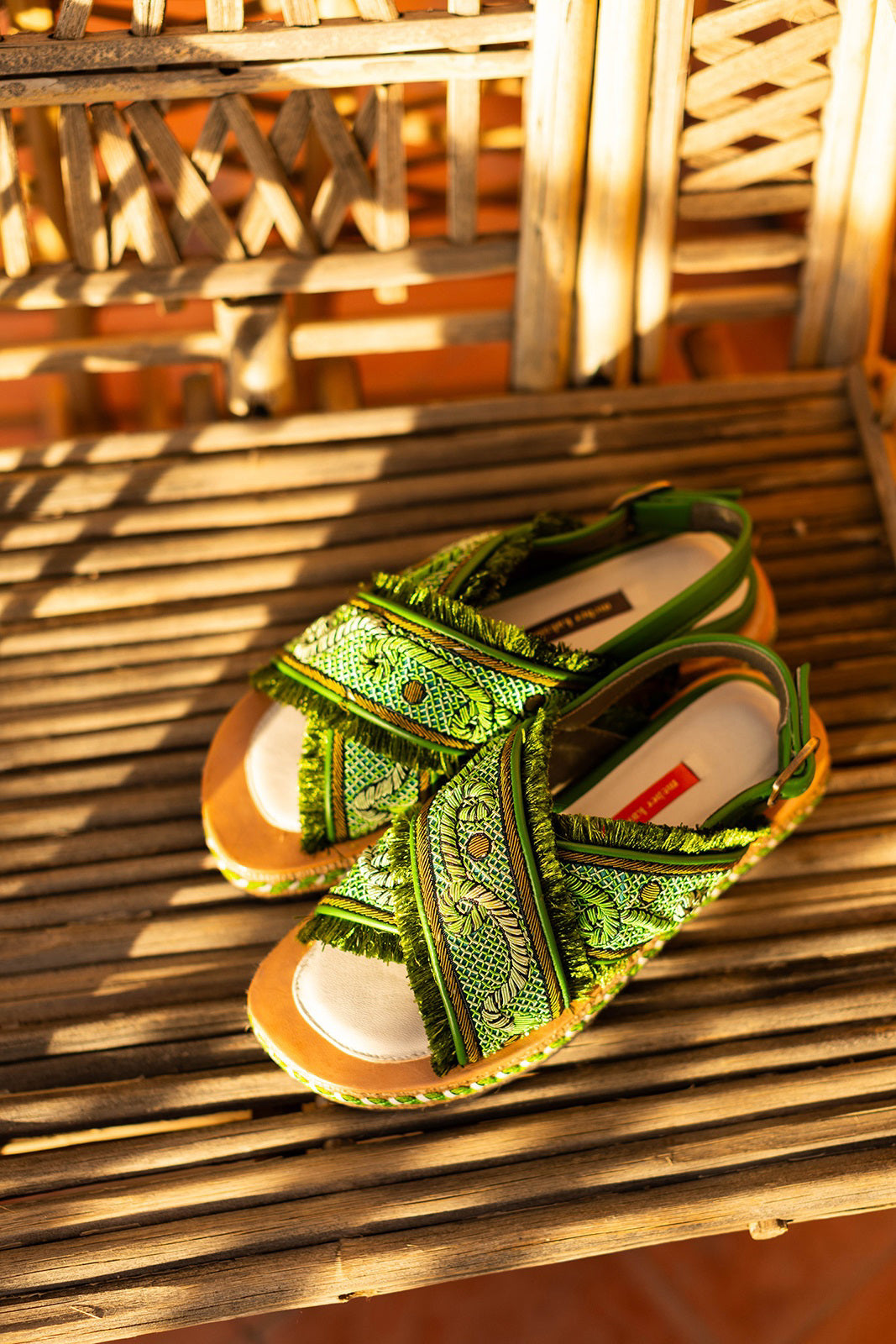 Explore the MEHER KAKALIA DA GAMMA BLOC sandal in Kelly Green Parrot, where comfort meets style. This open-toe sandal has a hand-embroidered design with fringe detailing, a thick textured sole with woven accents, an adjustable ankle strap, and a layered platform design.