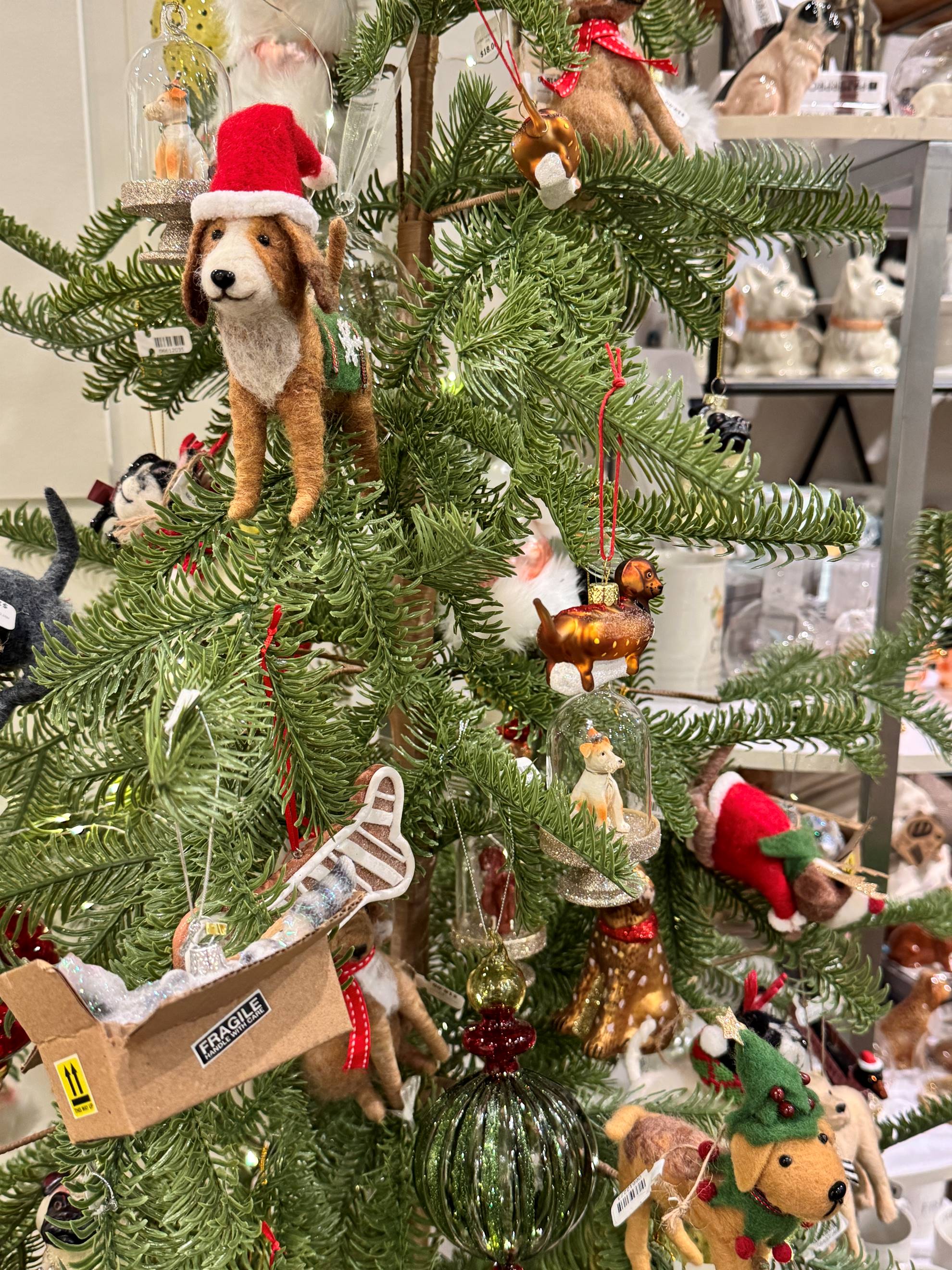 A Christmas tree decorated with various animal ornaments, including a dog in a Santa hat, a reindeer, and a mouse in a sleigh marked 