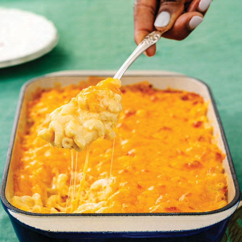 Person standing on a porch in front of a light blue house with a white door.