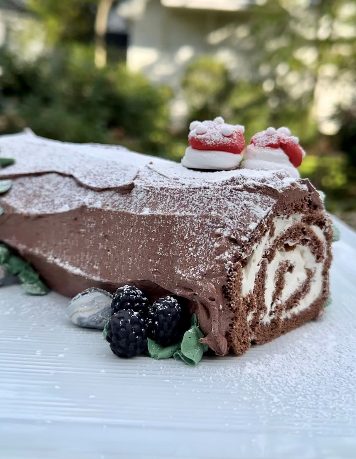 The FEARRINGTON VILLAGE Christmas Chocolate Yule Log features chocolate sponge cake, swirled cream filling, powdered sugar, marzipan décor, blackberries, and green leaves. Pickup December 24, 2025. A perfect holiday dessert!.