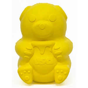 The TREAT DISPENSER HONEY BEAR (L) by SODA PUP is a durable, bright yellow rubber bear toy that holds a jar labeled "USA" with a dripping honey design. Made in the USA, it features rounded ears, circular eyes, a small nose, and detailed paws. This chew toy is also designed to dispense treats.