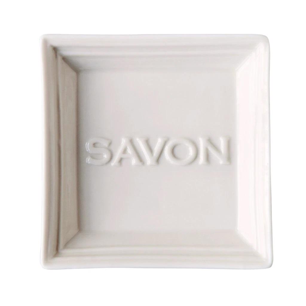 The SAVON SOAP DISH by EUROPEAN SOAPS, LLC is a square, white ceramic dish with the word 