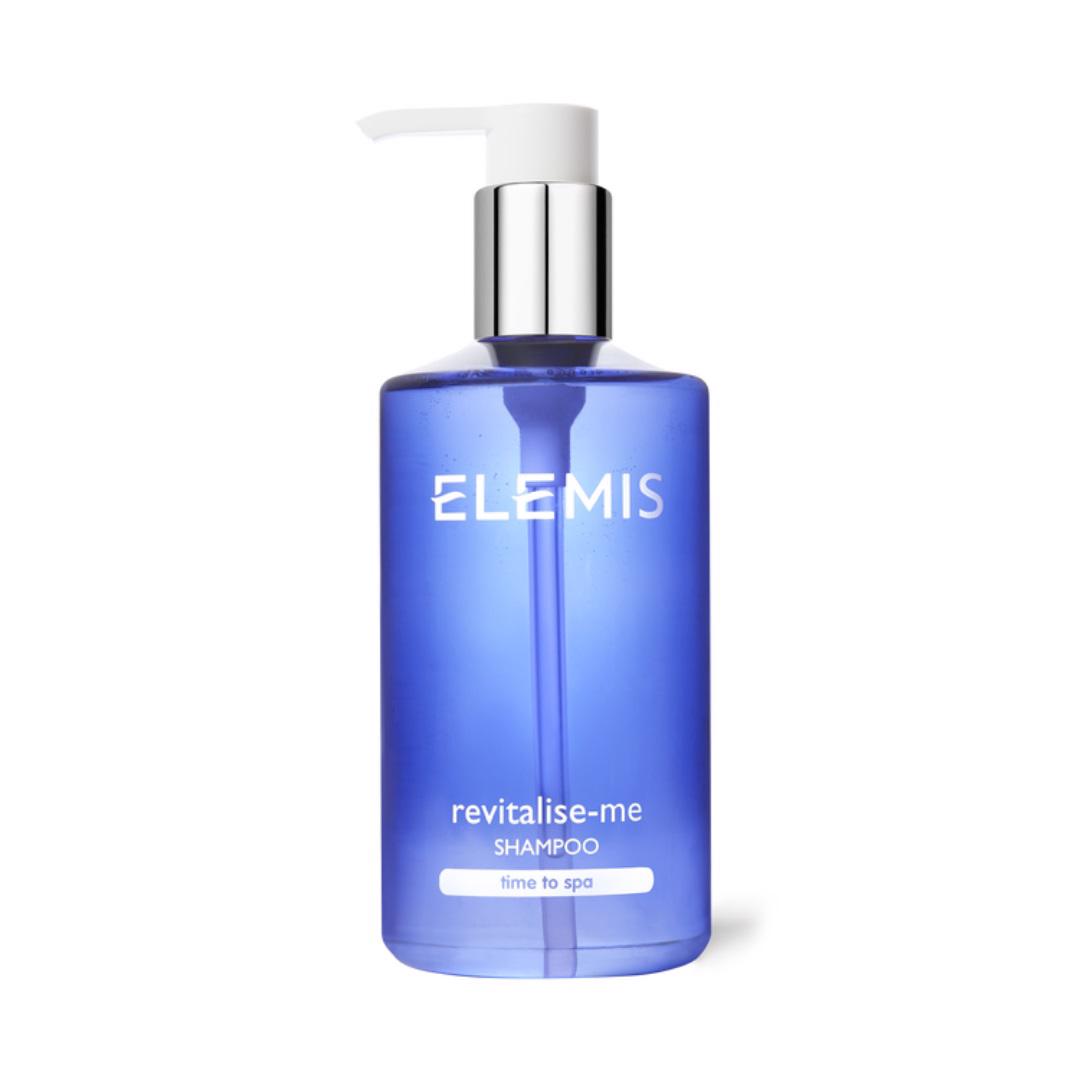 A blue ELEMIS - REVITALIZE ME SHAMPOO bottle from ELEMIS - STEINER with a silver and white pump dispenser at the top. The front of the bottle displays the product name along with &quot;time to spa&quot; in white text, promising an uplifting aromatic experience.