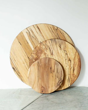 The ROUND SPALTED BOARD 20 by PETERMANS BOARDS & BOWLS INC is a handcrafted, round cutting board made from spalted maple. It boasts a natural grain pattern with a smooth finish. Featuring light and dark brown streaks, this upcycled wood decor piece beautifully showcases the organic texture and unique design of the wood.