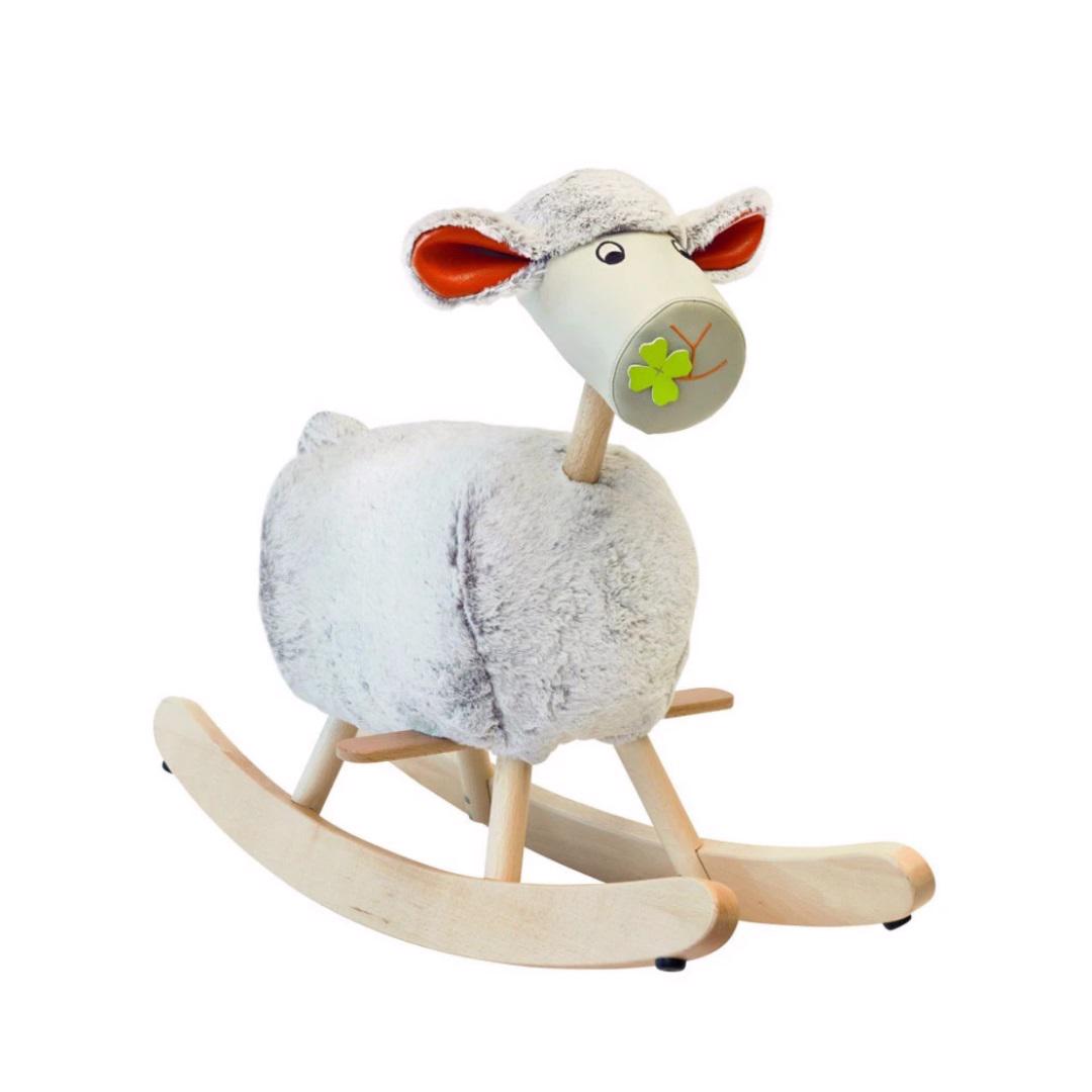 The LAMBCHOP ROCKING SHEEP by MAGIC FOREST, LTD is a delightful fluffy rocking sheep toy with a white body, wooden legs, and a pale wooden rocking base. This charming decorative piece features a cute, smiling face adorned with a green four-leaf clover on the snout and orange inner ears.