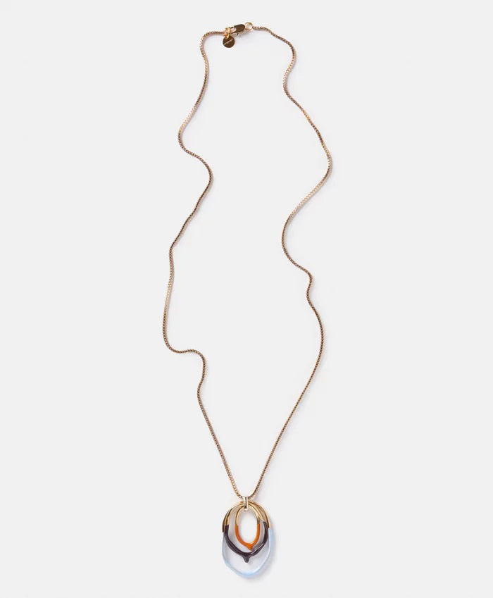 The DIP DYED NECKLACE by MOMONI is a long gold necklace featuring a delicate Venetian chain and interlocking oval pendants at the center. Made in Italy, the pendants showcase a layered look with gold, white, and coral colors. The necklace is displayed flat on a white background.