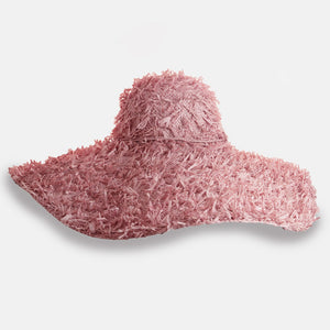 The SUMMERTIME HAT by SANS ARCIDET features a wide brim and a rustic, shaggy texture. Its loosely woven design offers a casual, bohemian vibe, with fringed crown and brim that enhance its rough, natural look. Perfect as a beach accessory, this adjustable hat stands out brilliantly against the plain white background.
