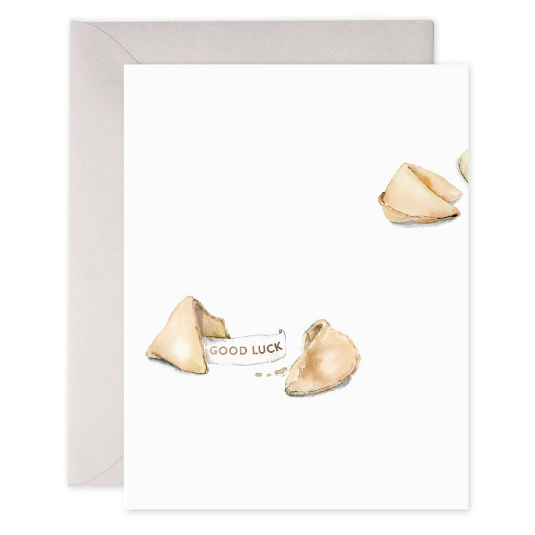 The E. FRANCES PAPER - FORTUNE COOKIE CARD by E. Frances Paper showcases a watercolor of an open fortune cookie with a "Good Luck" message and copper foil accents on a white background, adding charm to your wishes.