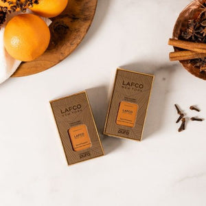 A rectangular, amber-colored bottle of LAFCO - SPICE POMANDER FOR PURA, featuring scents of cinnamon, bitter orange, and clove buds. The packaging is finished with a gray cap, while the brand name LAFCO and fragrance notes are printed on the front.